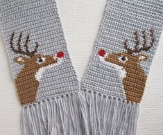 two crocheted deer mitts with red flowers on them