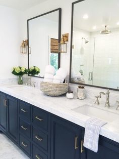 a bathroom with two sinks and mirrors on the wall, along with blue cabinetry