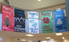 several colorful banners hanging from the ceiling in a school hallway with people walking around them