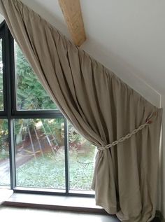 an open window with a curtain hanging from it's side in front of a wooden beam