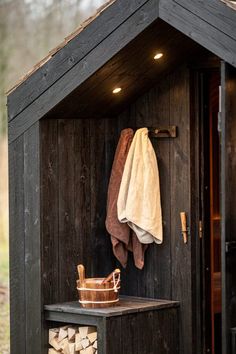 a towel hanging on the side of a wooden shed next to a pile of firewood