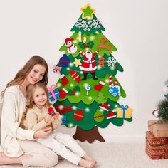 a woman and her daughter sitting in front of a christmas tree with decorations on it