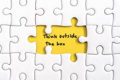 a yellow piece of puzzle with the words think outside the box written on it in black