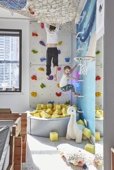 two children are climbing up and down the wall in a room with rocks, foams and toys