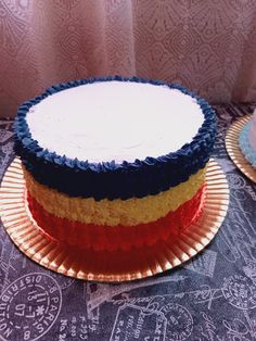 two cakes with different colored frosting sitting on a table