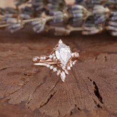 a close up of a ring on top of a piece of wood with flowers in the background