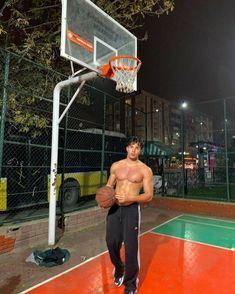 a man standing in front of a basketball hoop with his shirt off and no shirt on