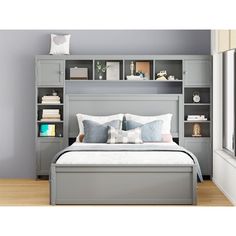 a bed sitting under a window next to a book shelf filled with books and pillows