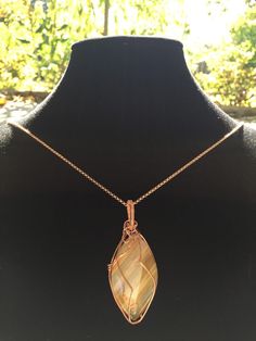 This pendant is made with a unique piece of brown, yellow, and white striped agate. It is wrapped with copper wire and comes with an optional copper chain. Hand Wrapped Gold Agate Necklaces, Hand Wrapped Gold Agate Necklace, Wire Wrapped Copper Wire Necklace With Round Pendant, Wire Wrapped Round Pendant Necklace In Copper, Amber Agate Wire Wrapped Necklace, Brown Hand Wrapped Pendant Necklace, Hand Wrapped Brown Pendant Necklace, Hand Wrapped Copper Gold Necklace, Hand Wrapped Gold Necklace With Copper Wire