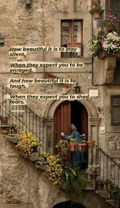 an old building with some flowers on the balcony and a man standing at the door