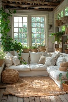 a living room filled with lots of white couches and pillows on top of a wooden floor