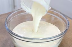 a glass bowl filled with cream sitting on top of a wooden table