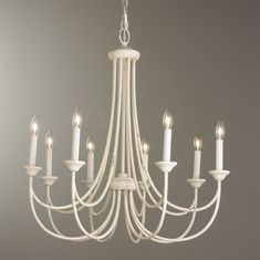 a white chandelier with six candles hanging from it's center and four arms