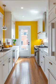 a kitchen with yellow walls, white cabinets and wood floors is pictured in this image