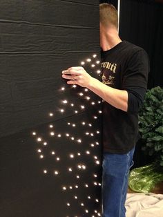 a man standing in front of a black wall with white lights on it's side