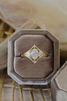 an antique diamond ring sits in a velvet box on a wicker chair with the lid open