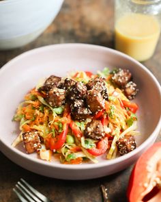 a white bowl filled with meatballs and veggies next to a glass of orange juice