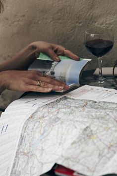 a woman sitting at a table with two glasses of wine and a map in front of her