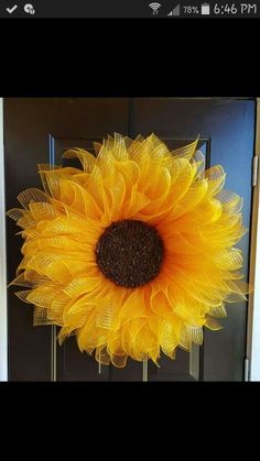 a large sunflower is hanging on the front door to decorate it's entrance