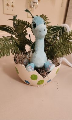 a stuffed animal sitting in an egg shell with plants growing out of the eggshell