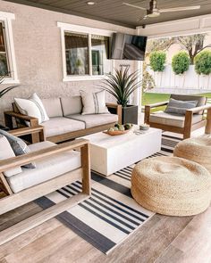 an outdoor living area with couches, chairs and rugs on the wooden floor