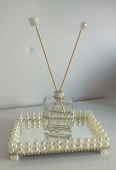 two toothbrushes sticking out of a glass container with pearls on the bottom and handles