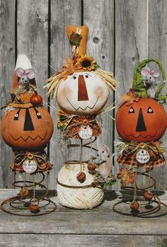 three pumpkins with faces on them are sitting in front of a wooden fence,