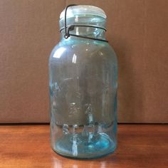 a blue glass jar sitting on top of a wooden table next to a brown wall