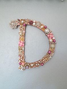 the letter d is decorated with pink and white beads