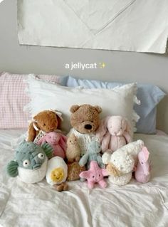 there are many stuffed animals laying on the bed with pillows and pillow cases in front of them