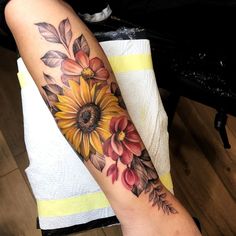 a woman's arm with flowers and leaves on it