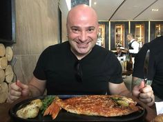 a bald man sitting at a table with a plate of food in front of him