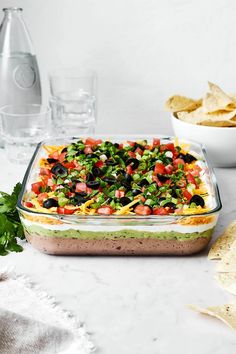 a glass casserole dish filled with vegetables and tortilla chips