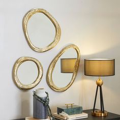 three circular mirrors mounted on the wall above a desk with a lamp and book next to it