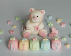 a small teddy bear sitting next to some letters and butterflies on a gray surface with the word happy spelled out