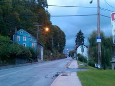 an empty street at dusk with no cars on the road and houses in the background