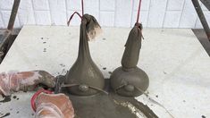 two vases sitting on top of a cement slab next to a red object with wires hanging from it