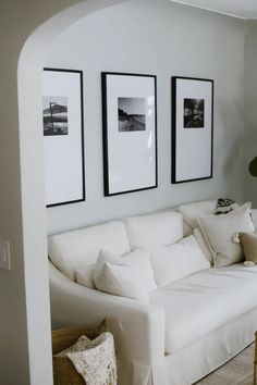 a living room with white couches and pictures on the wall