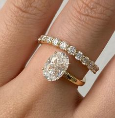 a woman's hand with a diamond ring on top of her finger and an engagement band