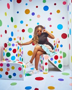 a woman sitting on top of a white bench surrounded by multicolored polka dots