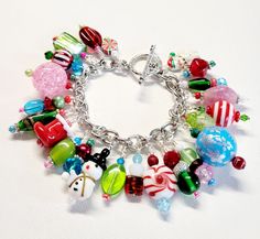 a close up of a bracelet on a white surface with beads and charms around it