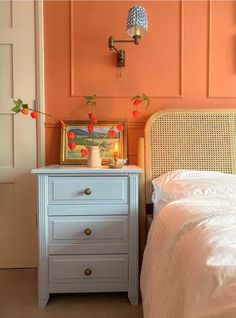 a bedroom with an orange wall and white bed