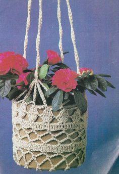 a crocheted bag with flowers hanging from it's sides and two handles