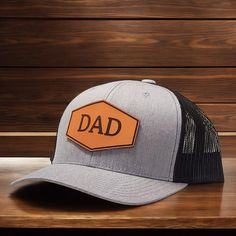 Dad Hat leather patch trucker hat. All patches are engraved on 100% veg-tanned leather. Once engraved, your custom leather patch is cut, dyed and sealed before pressing it onto your hat. These hats are great for new Dad gift ideas, new Papa hat, gift from kids, Dad hat, Grandpa hat, Daddy Hat, Pawpaw Gift, grandpa Gift, custom hat, trucker hat for Dad, gift for husband, Dad snapback hat, stepdad baseball hat. Makes a good Christmas present or Father's Day gift for the best Dad. Richardson 112 Sp Customizable Black Trucker Hat For Father's Day, Father's Day Snapback Trucker Hat With Leather Patch, Customizable One-size Dad Hat, Father’s Day Trucker Hat With Curved Bill, Personalized Dad Hat, One Size Fits Most, Birthday Gift For Husband, Dad Gift Ideas, New Dad Gift, Father Christmas Gifts