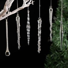 an assortment of crystal ornaments hanging from a branch with a christmas tree in the background