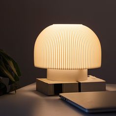 a white lamp sitting on top of a table next to a laptop