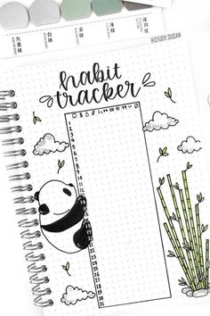 an open notebook with the words habit tracker written on it next to some pens and pencils