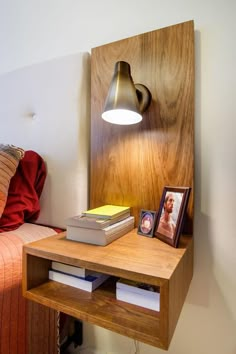 a bed with a wooden headboard next to a lamp and books on a table