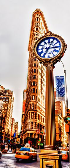 a clock tower in the middle of a busy city street with taxis and cabs