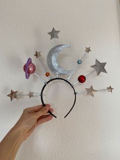 a hand holding a headband with stars and moon decorations on it